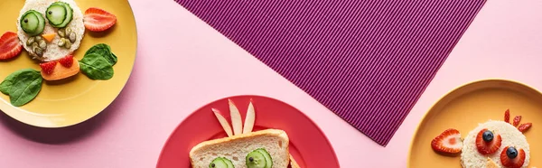 Vista superior de platos con animales de lujo hechos de comida sobre fondo rosa y púrpura - foto de stock