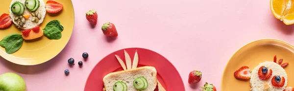 Vista dall'alto di piatti con animali di fantasia fatti di cibo su sfondo rosa con frutta, colpo panoramico — Foto stock