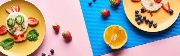 Vue de dessus des assiettes avec des animaux de fantaisie faits de nourriture sur fond bleu et rose avec des fruits, vue panoramique — Photo de stock