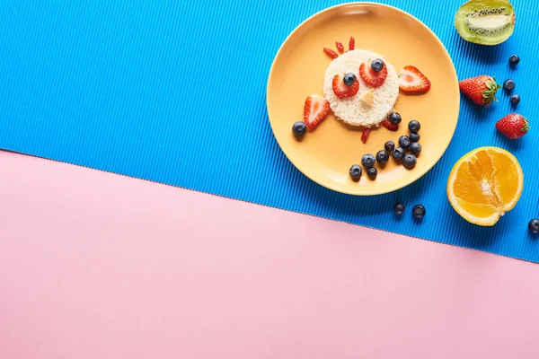 Vue de dessus de la plaque avec un animal de fantaisie fait de nourriture sur fond bleu et rose — Photo de stock