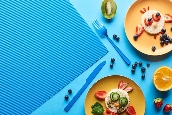 Vista dall'alto di piatti con animali fantasia fatti di cibo su sfondo blu — Foto stock