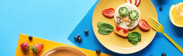 Top view of plate with fancy animal made of food on blue and yellow background, panoramic shot — Stock Photo