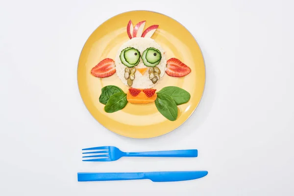 Vue du dessus de l'assiette avec vache de fantaisie faite de nourriture pour le petit déjeuner des enfants près de couverts sur fond blanc — Photo de stock