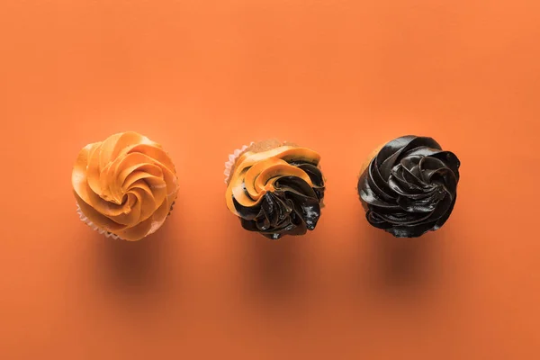 Vista superior de deliciosos cupcakes de Halloween sobre fondo naranja - foto de stock