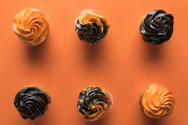 Vista superior de deliciosos cupcakes de Halloween sobre fondo naranja con espacio de copia - foto de stock