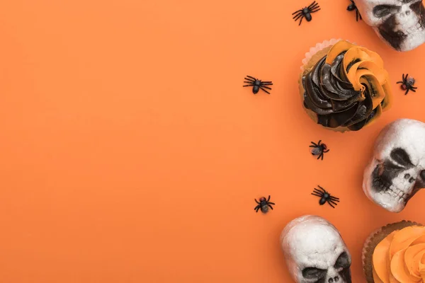 Vue du dessus de délicieux cupcakes d'Halloween avec des araignées et des crânes sur fond orange avec espace de copie — Photo de stock