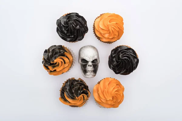 Vista superior de deliciosos cupcakes de Halloween em torno do crânio isolado no branco — Fotografia de Stock