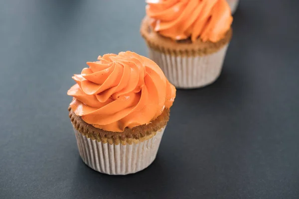 Deliciosos cupcakes de naranja de Halloween sobre fondo negro - foto de stock