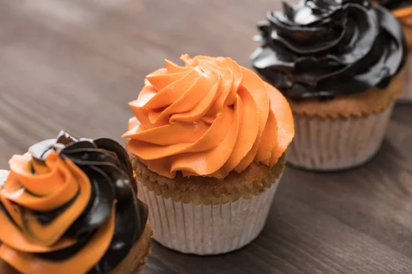 Вкусный Хэллоуин черные и оранжевые кексы на деревянный стол — стоковое фото