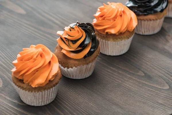 Deliziosi cupcake neri e arancioni di Halloween sul tavolo di legno — Foto stock