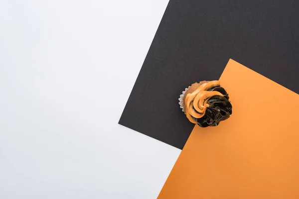 Vue du dessus de délicieux cupcake d'Halloween sur fond orange, noir et blanc avec espace de copie — Photo de stock