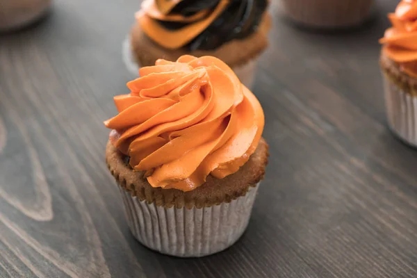 Foco seletivo de delicioso cupcake de laranja de Halloween na mesa de madeira — Fotografia de Stock