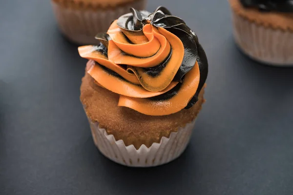 Foco seletivo de delicioso cupcake laranja de Halloween no fundo preto — Fotografia de Stock