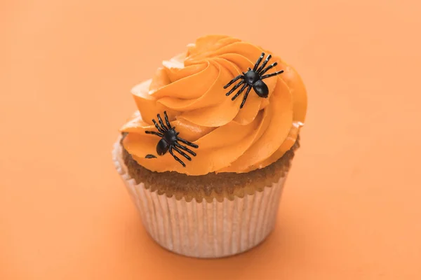 Espeluznante cupcake de Halloween con arañas sobre fondo naranja - foto de stock