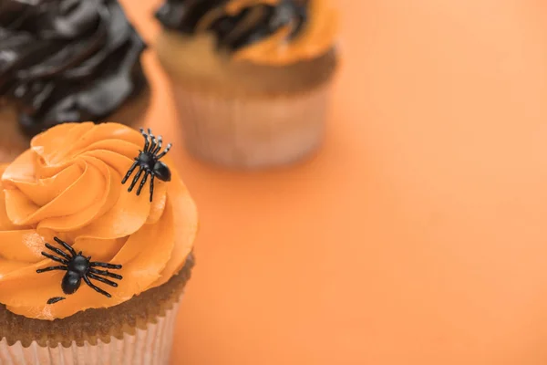 Foco selectivo de espeluznante cupcake de Halloween con arañas sobre fondo naranja - foto de stock