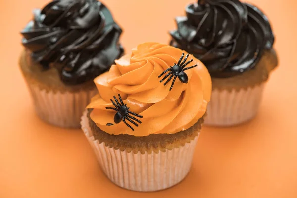 Foco seletivo de deliciosos cupcakes de Halloween com aranhas no fundo laranja — Fotografia de Stock