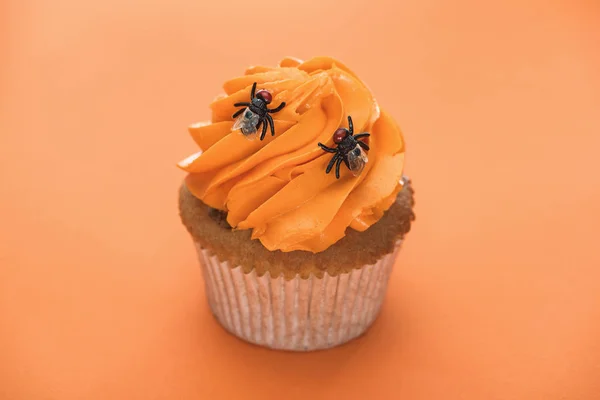 Saboroso cupcake de Halloween com aranhas no fundo laranja — Fotografia de Stock