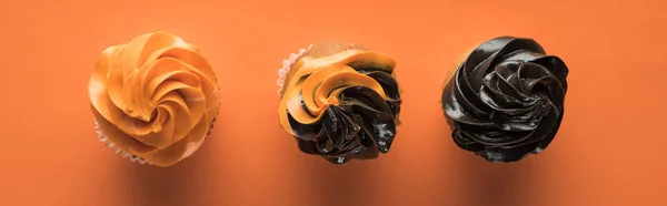 Top view of delicious Halloween cupcakes on orange background, panoramic shot — Stock Photo