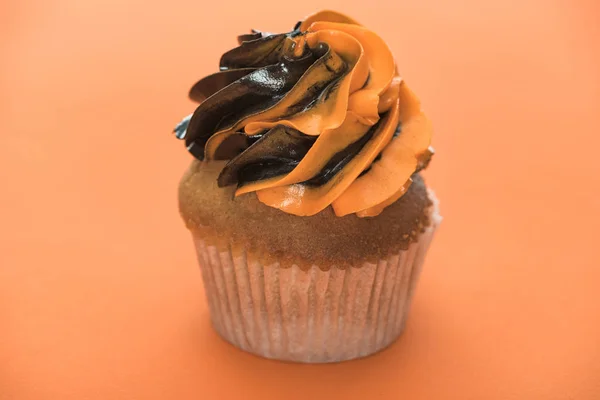 Delicioso cupcake de Halloween sobre fondo naranja - foto de stock