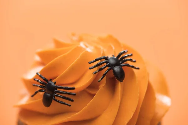 Close up view of spooky Halloween cupcake with spiders on cream isolated on orange — Stock Photo