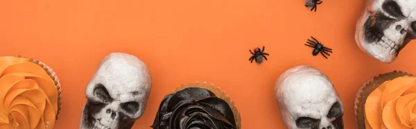 Vista superior de cupcakes, crânios decorativos e aranhas em fundo laranja com espaço de cópia, tiro panorâmico — Fotografia de Stock