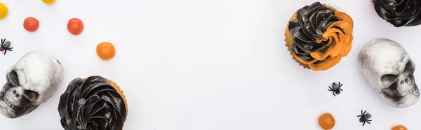Vista superior de deliciosos cupcakes de Halloween con arañas, calaveras y bombones sobre fondo blanco, plano panorámico - foto de stock