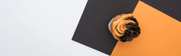 Вид сверху на вкусный кекс Хэллоуин на черном, оранжевом и белом фоне с копировальным пространством, панорамный снимок — стоковое фото