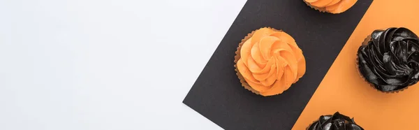 Vista superior de deliciosos cupcakes de Halloween em fundo preto, laranja e branco com espaço de cópia, tiro panorâmico — Fotografia de Stock