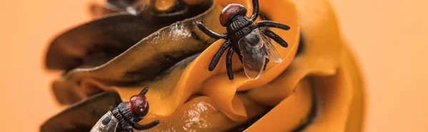 Close up view of spooky Halloween cupcake with flies on cream isolated on orange, panoramic shot — Stock Photo