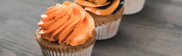 Fuoco selettivo di delizioso cupcake arancione di Halloween su tavolo di legno, colpo panoramico — Foto stock