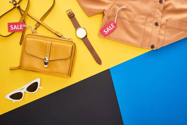 Vista dall'alto di camicia e accessori con etichette di vendita su sfondo blu, giallo e nero — Foto stock