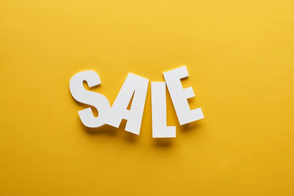 Vista superior de lettering venda branca no fundo amarelo — Fotografia de Stock