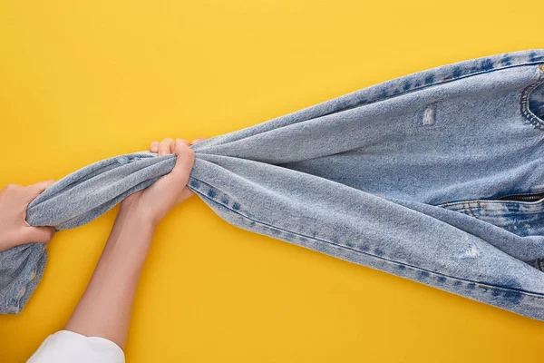 Top view of woman pulling jeans on yellow background — Stock Photo