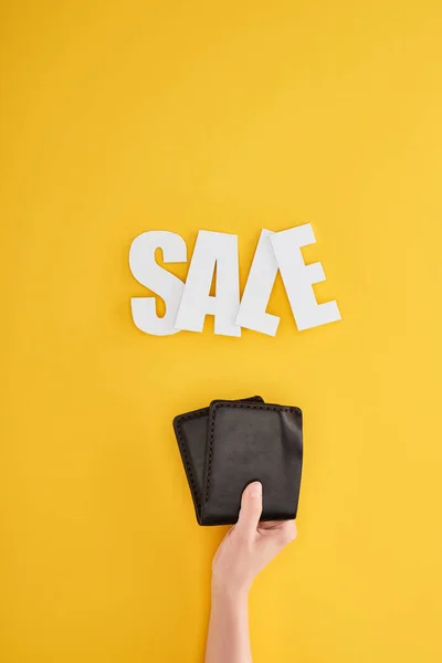 Vue recadrée de femme tenant portefeuille avec vente lettrage sur fond jaune — Photo de stock