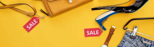 Top view of fashionable clothing with sale labels on yellow background, panoramic shot — Stock Photo