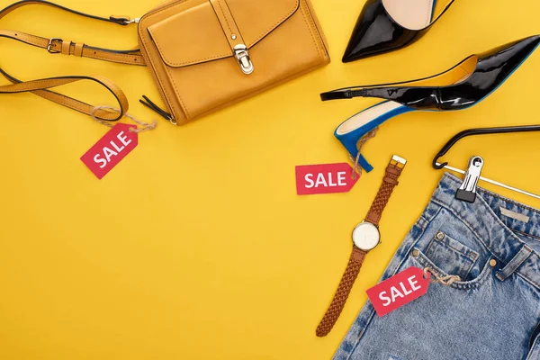 Top view of fashionable clothing and accessories with sale labels on yellow background — Stock Photo