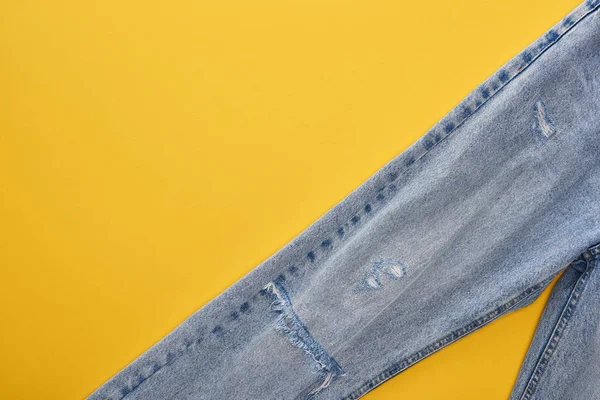 Top view of fashionable jeans on yellow background — Stock Photo