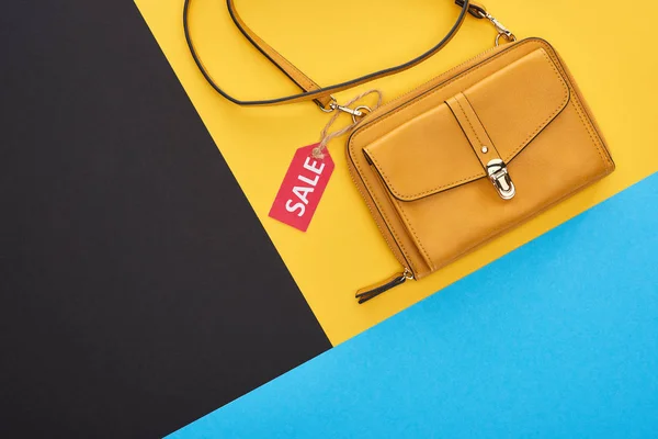 Vue du dessus du sac avec étiquette de vente sur fond bleu, jaune et noir — Photo de stock