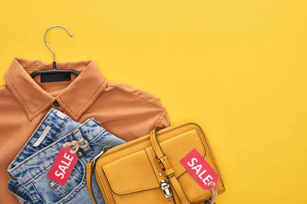 Draufsicht auf Tasche, Hemd und Jeans mit Verkaufsetiketten isoliert auf gelb — Stockfoto