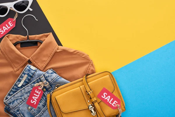 Vista dall'alto di abiti e accessori con etichette di vendita su sfondo blu, giallo e nero — Foto stock