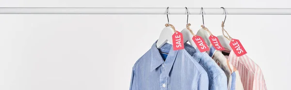 Camisas elegantes penduradas com etiquetas de venda isoladas em branco, tiro panorâmico — Fotografia de Stock