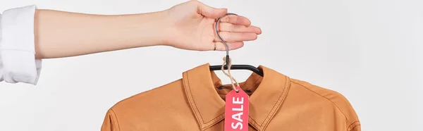Cropped view of woman holding elegant shirt with sale label isolated on white, panoramic shot — Stock Photo