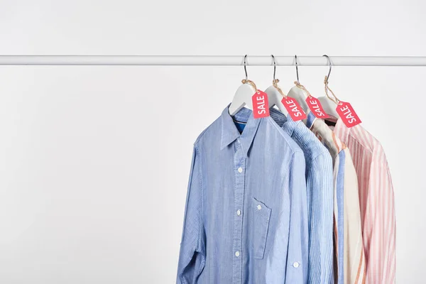 Elegantes camisas colgando con etiquetas de venta aisladas en blanco - foto de stock