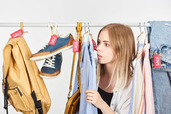 Menina loira em roupas da moda penduradas com etiquetas de venda isoladas em branco — Fotografia de Stock