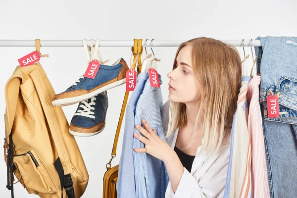 Chica rubia en ropa colgando con etiquetas de venta aisladas en blanco - foto de stock