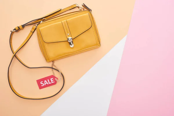 Draufsicht der Tasche mit Verkaufsetikett auf beigem, weißem und rosa Hintergrund — Stockfoto