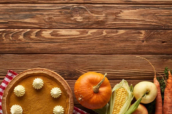 Vista dall'alto della tovaglia a quadretti con frutta, verdura e torta di zucca autunnale su superficie di legno con spazio per copiare — Foto stock