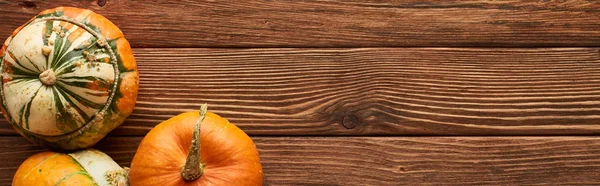 Panoramic shot of raw pumpkins on brown wooden surface — Stock Photo