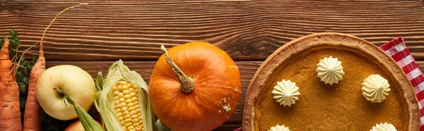 Panoramic shot of checkered tablecloth with autumn fruit, vegetables and pumpkin pie on wooden surface — Stock Photo