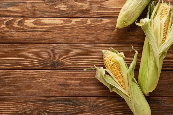 Top view of uncooked sweet corn on wooden surface — Stock Photo